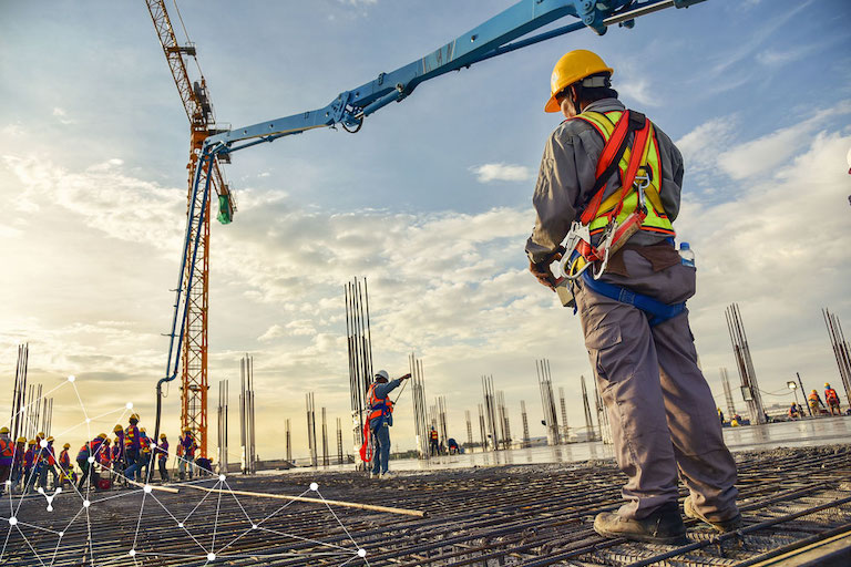 software gestione del personale per edilizia e costruzioni : un uomo in tuta da lavoro in un cantiere in costruzione