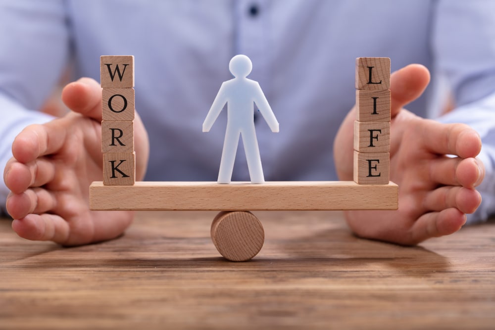 work-life balance: persona che tiene in equilibrio blocchi di legno su un'asse