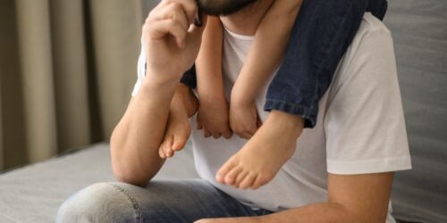 congedo parentale: uomo che tiene sulle spalle un bambino