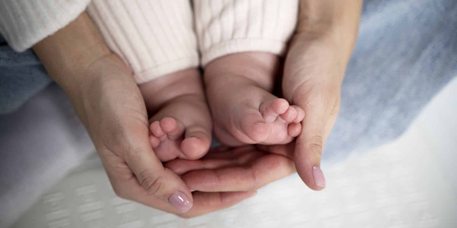 a chi spetta il congedo parentale: donna che sostiene i piedi di un neonato