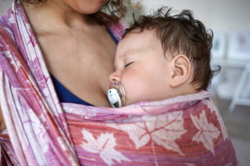 primo piano di neonato che dorme sul seno della madre