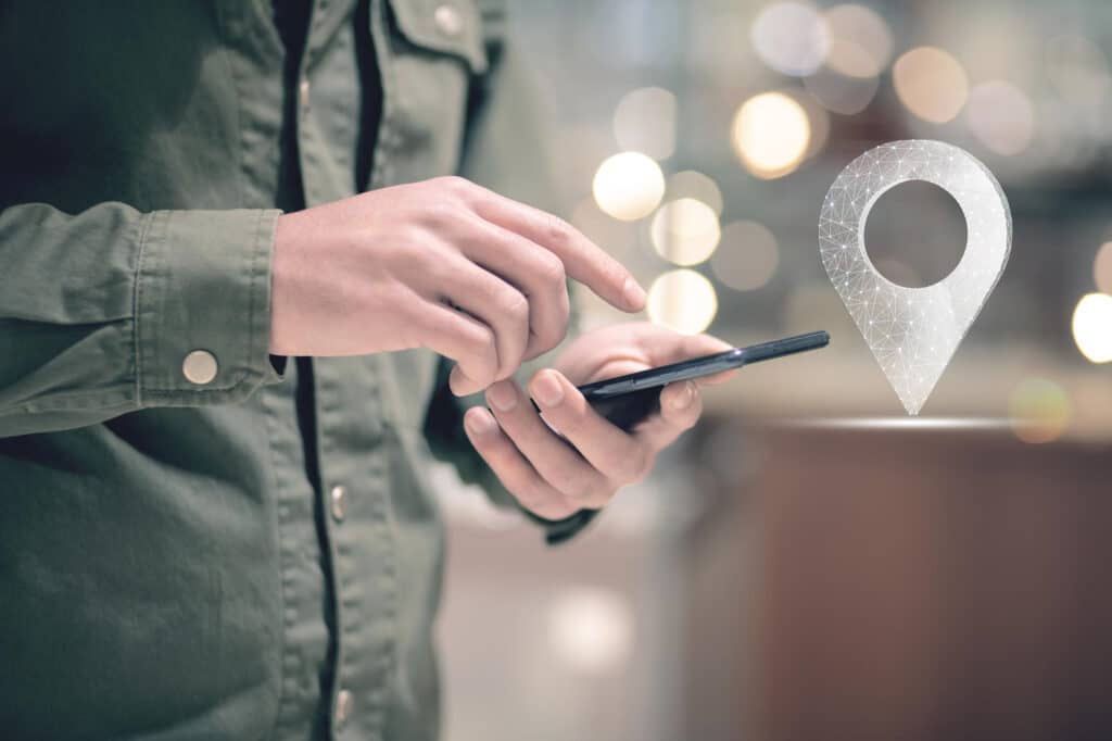 primo piano di persona che clicca sullo schermo del proprio smartphone e icona di geolocalizzazione per la timbratura geolocalizzata