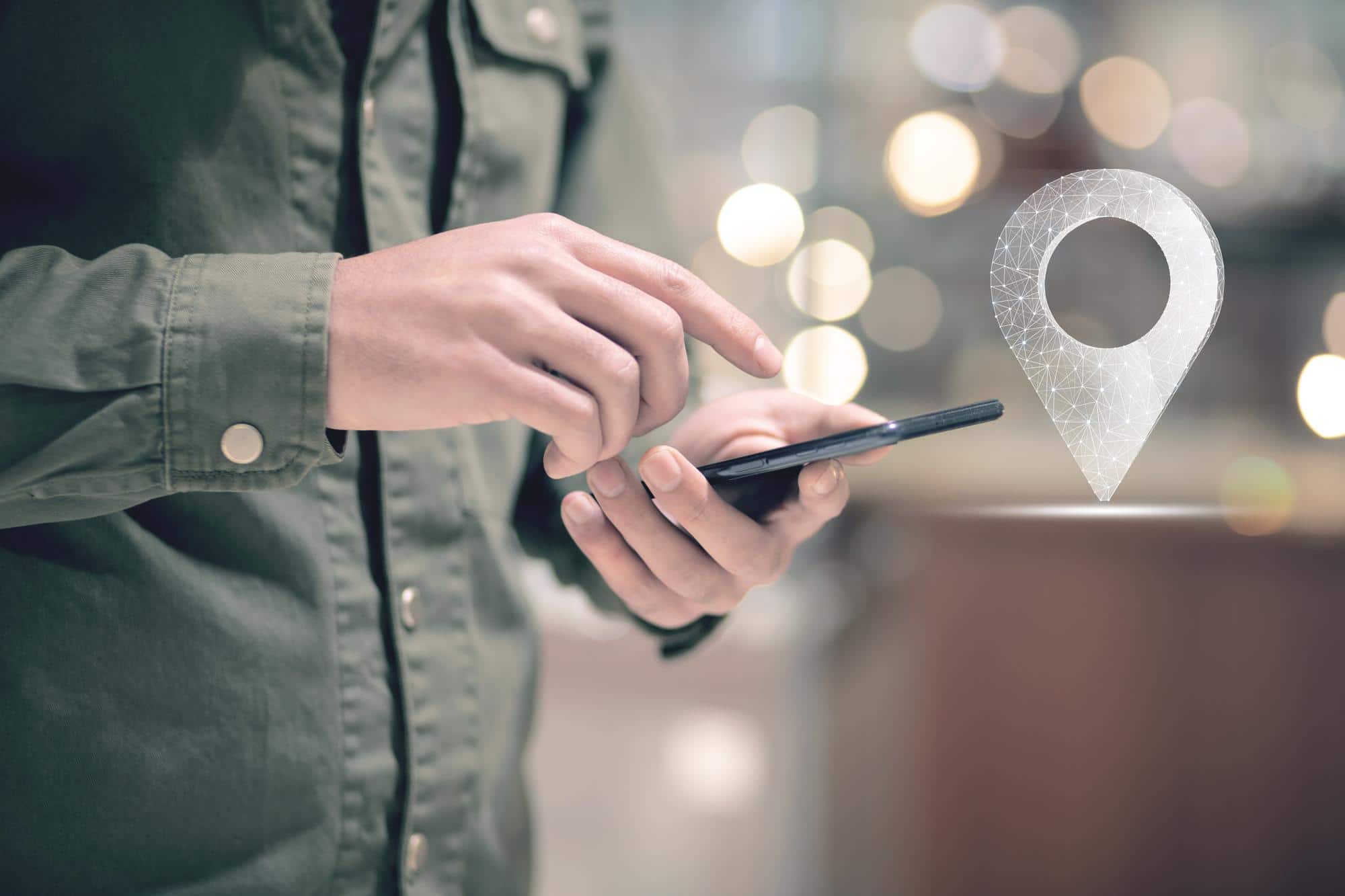 App timbratura geolocalizzata: come funziona e perché semplifica la gestione presenze primo piano di persona che clicca sullo schermo del proprio smartphone e icona di geolocalizzazione per la timbratura geolocalizzata